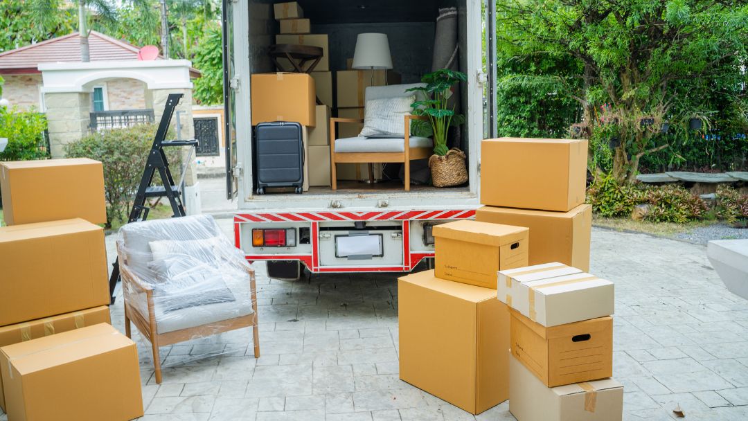 rear view of moving truck with boxes inside of truck and stacked outside on ground